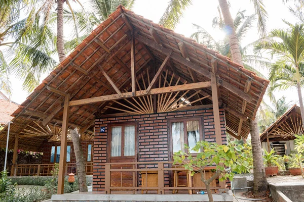 Bungalows confortables en brique rouge avec un toit en bois parmi les palmiers — Photo