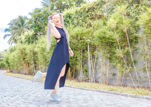 나무 사이 검은 드레스와 선글라스 땋은 소녀 산책 — 스톡 사진