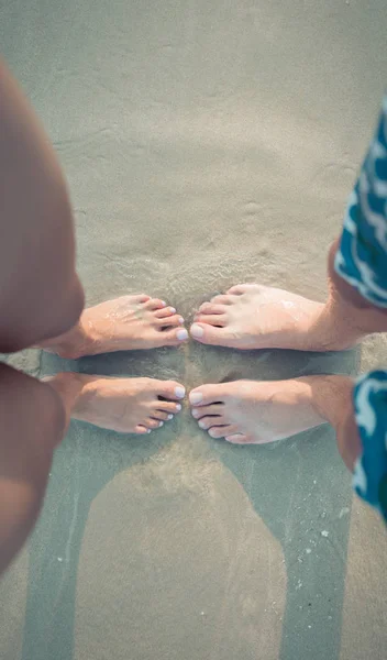 Manliga och kvinnliga fötter på sanden — Stockfoto