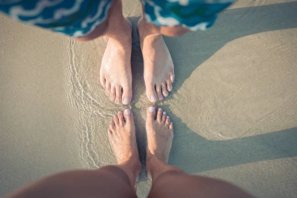 Manliga och kvinnliga fötter på sanden — Stockfoto