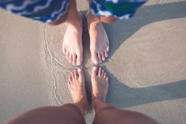 kum üzerinde erkek ve kadın ayakları