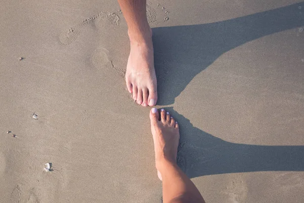 En hane och en kvinnlig fot på sanden — Stockfoto