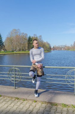 bir korkuluk nehrin yanında oturan beyaz spor giyim çekici adam