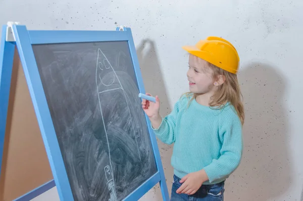 儿童工程师 设计师 戴头盔的女孩在黑色粉笔板上粉刷房子 — 图库照片