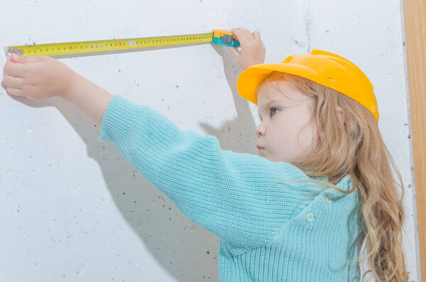 child worker, Builder, girl in a helmet measures the distance with a tape measure