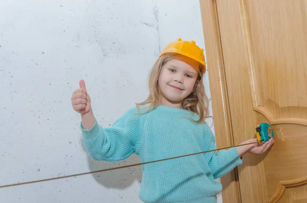 çocuk işçisi, Builder, bir kask kız bir bant ölçüsü ile mesafe ölçer