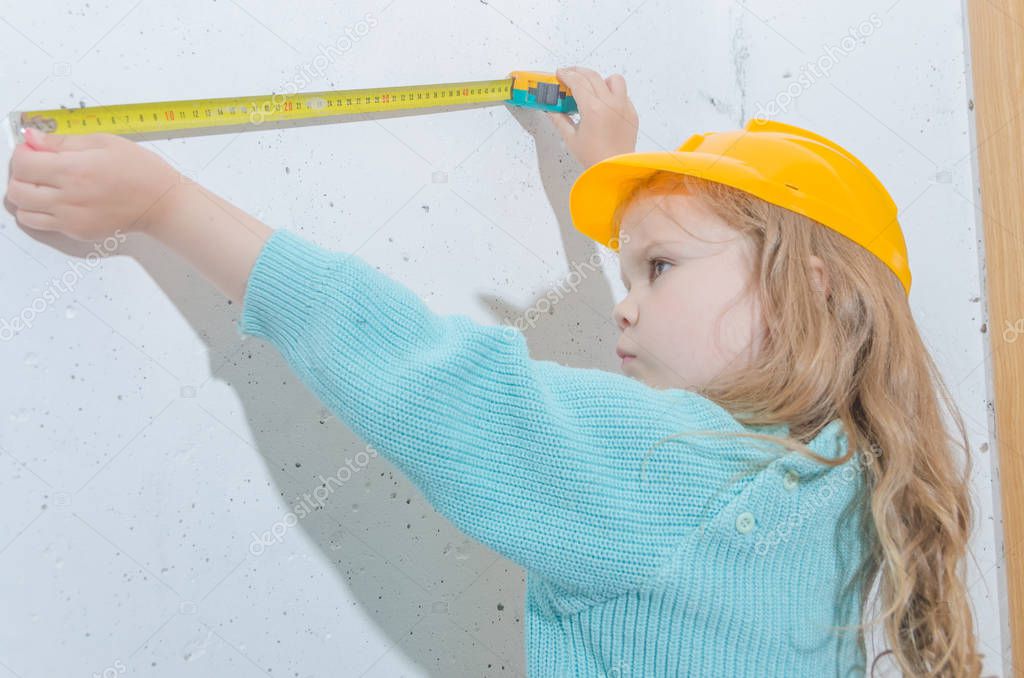 child worker, Builder, girl in a helmet measures the distance with a tape measure