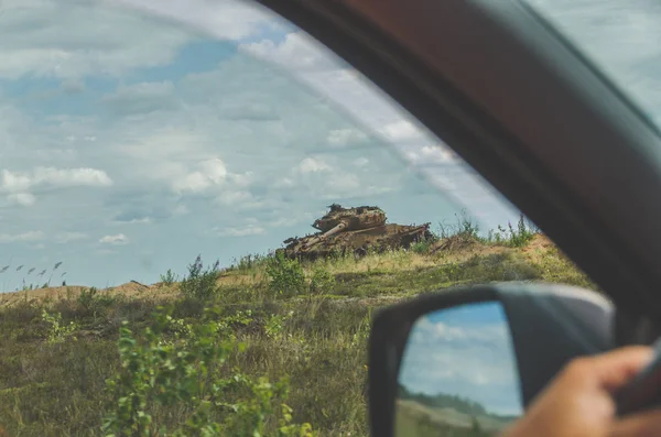 車のホイールの後ろに 錆びた戦車で戦場を見ることができます — ストック写真