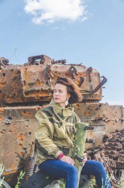 Güneşli bir gün kız kırık bir tank savaş alanında arka plan üzerinde bazukayla üniformalı