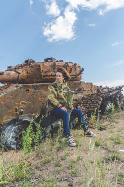 Güneşli bir gün kız kırık bir tank savaş alanında arka plan üzerinde bazukayla üniformalı
