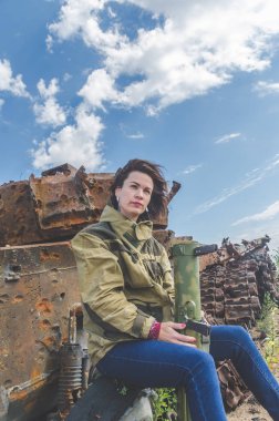 Güneşli bir gün kız kırık bir tank savaş alanında arka plan üzerinde bazukayla üniformalı
