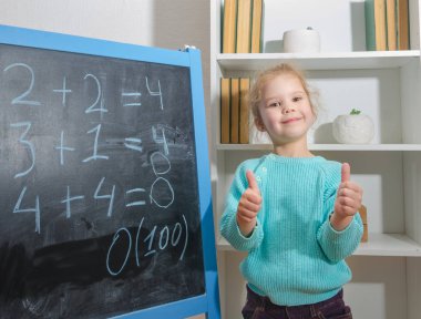 Kız, bir öğrenci bir kara tahta üzerinde matematiksel örnekler çözdü.