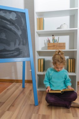 Kız, bir çocuk tebeşir tahta oturan bir kitap okuma