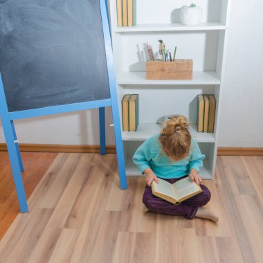 Kız, bir çocuk tebeşir tahta oturan bir kitap okuma