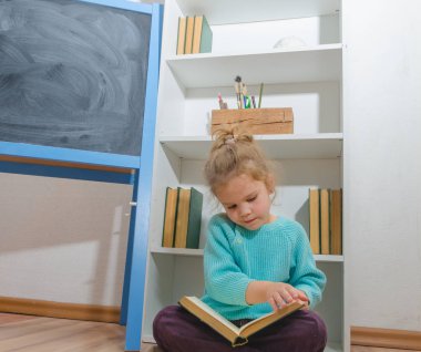 Kız, bir çocuk tebeşir tahta oturan bir kitap okuma