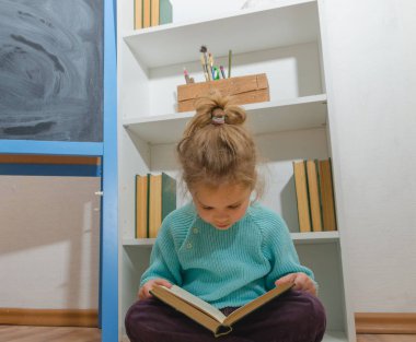 Kız, bir çocuk tebeşir tahta oturan bir kitap okuma