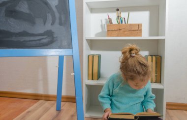 Kız, bir çocuk tebeşir tahta oturan bir kitap okuma