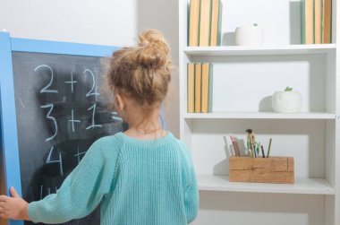 Kız, bir öğrenci bir kara tahta üzerinde matematiksel örnekler çözdü.