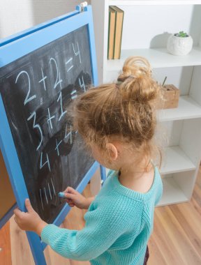 Kız, bir öğrenci bir kara tahta üzerinde matematiksel örnekler çözdü.