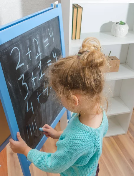 Kız, bir öğrenci bir kara tahta üzerinde matematiksel örnekler çözdü.