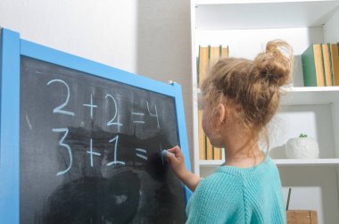 Kız, bir öğrenci bir kara tahta üzerinde matematiksel örnekler çözdü.