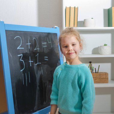 Kız, bir öğrenci bir kara tahta üzerinde matematiksel örnekler çözdü.