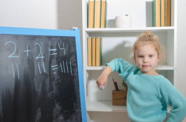 Kız, bir öğrenci bir kara tahta üzerinde matematiksel örnekler çözdü.