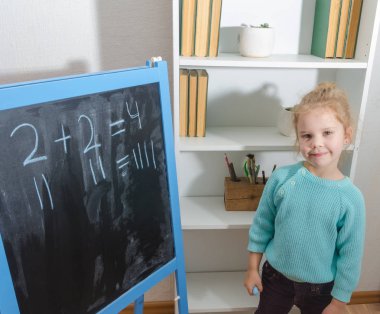 Kız, bir öğrenci bir kara tahta üzerinde matematiksel örnekler çözdü.