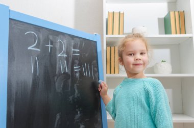 Kız, bir öğrenci bir kara tahta üzerinde matematiksel örnekler çözdü.