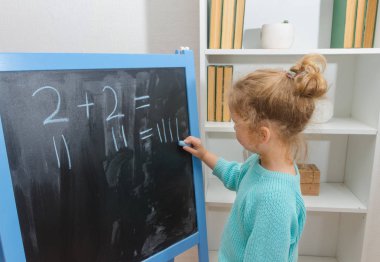 Kız, bir öğrenci bir kara tahta üzerinde matematiksel örnekler çözdü.