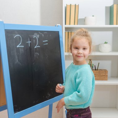 Kız, bir öğrenci bir kara tahta üzerinde matematiksel örnekler çözdü.