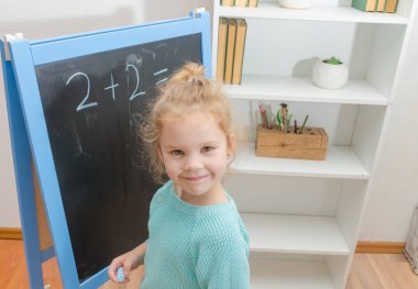 Kız, bir öğrenci bir kara tahta üzerinde matematiksel örnekler çözdü.