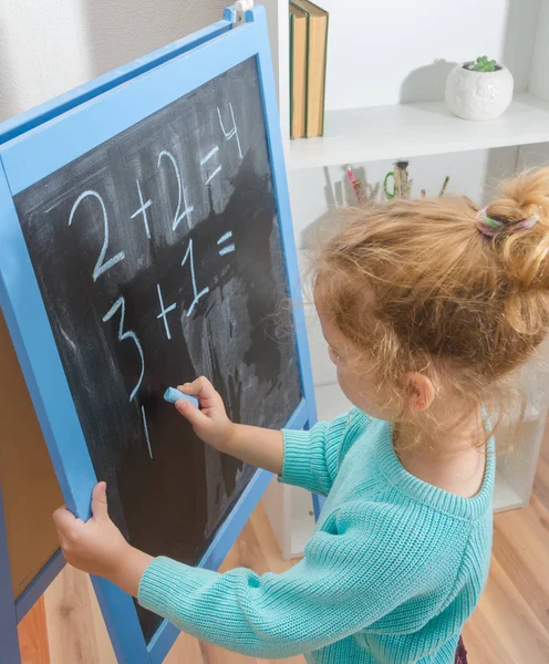 Kız, bir öğrenci bir kara tahta üzerinde matematiksel örnekler çözdü.