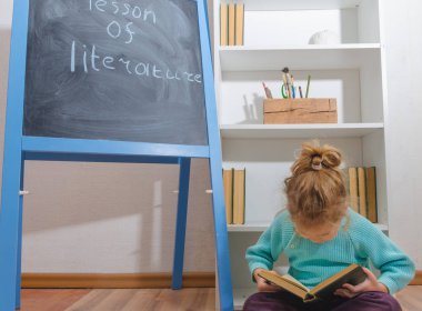 Kız, bir çocuk ile yazıt edebiyat ders kurulu tebeşir yakınındaki bir kitapla