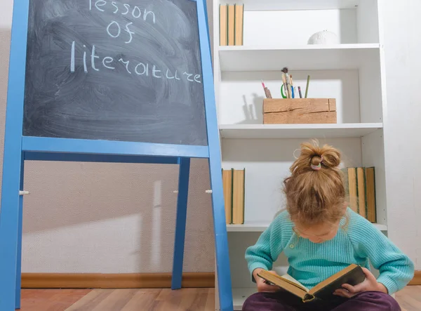 Kız, bir çocuk ile yazıt edebiyat ders kurulu tebeşir yakınındaki bir kitapla