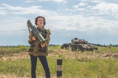 elleri yok şekildepaslı savaş alanında arka plan üzerinde de bir bazuka ile askeri üniforma ve kot pantolon güzel kız