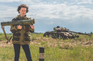 elleri yok şekildepaslı savaş alanında arka plan üzerinde de bir bazuka ile askeri üniforma ve kot pantolon güzel kız