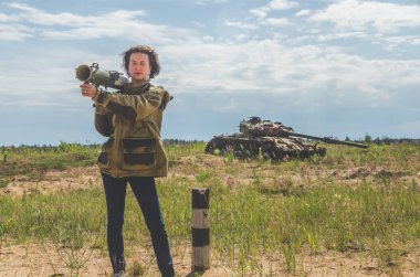 elleri yok şekildepaslı savaş alanında arka plan üzerinde de bir bazuka ile askeri üniforma ve kot pantolon güzel kız