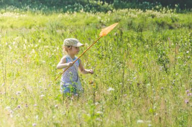 Kız, bir net bir çocukla bir kelebek bir güneşli yaz gününde yakalar