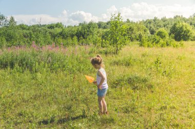 Kız, bir net bir çocukla bir kelebek bir güneşli yaz gününde yakalar