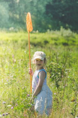 Kız, bir net bir çocukla bir kelebek bir güneşli yaz gününde yakalar