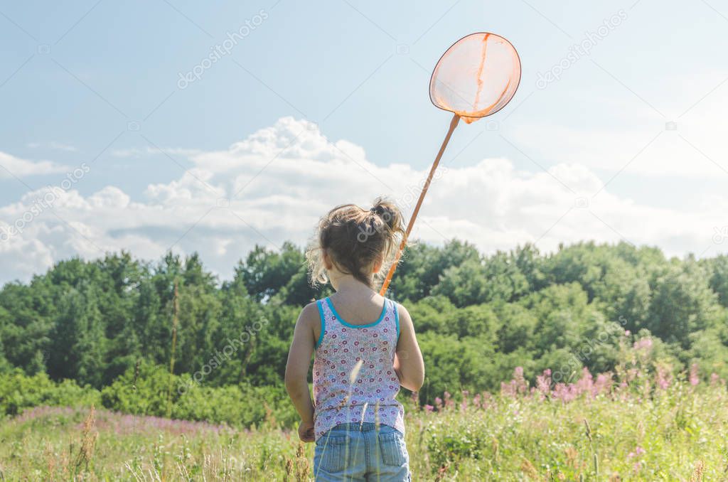 girl, a child with a net catches a butterfly on a Sunny summer day