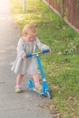 Güneşli yaz günü bir kız ve bir çocuk scooter üzerinde