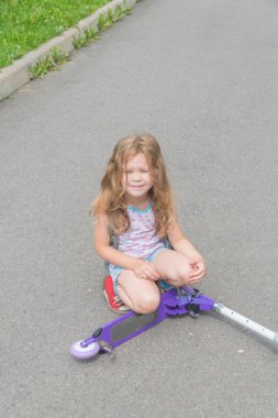 bir kız, bir çocuk bir Scooter'dan ve acı çığlık onun diz zarar