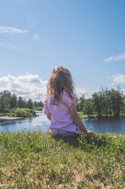 suya yakın bir kayanın üzerine oturmuş çocuk