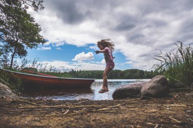 Kız, bir çocuk yürür su, göl, nehir, yakınındaki ormanda tekne