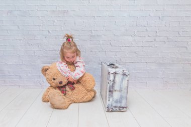 Kız, Çocuk ayı ve Bavula beyaz tuğla ile arka plan duvar