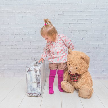 Kız, Çocuk ayı ve Bavula beyaz tuğla ile arka plan duvar