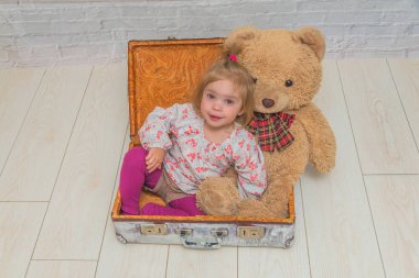 Kız, Çocuk ayı ve Bavula beyaz tuğla ile arka plan duvar