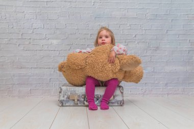 Kız, Çocuk ayı ve Bavula beyaz tuğla ile arka plan duvar